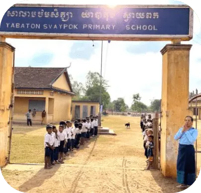 Cambodian children waiting in front of the school gates, making a flower path